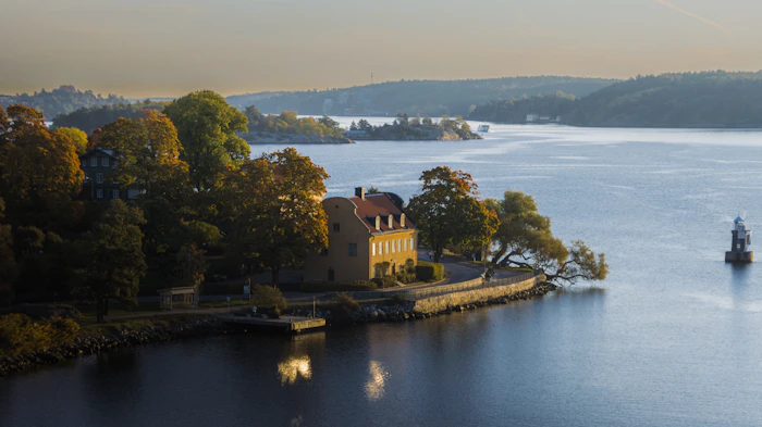 Maison jaune au bord d'un bras de mer boisé